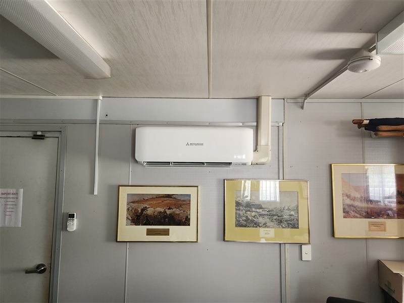 A wall-mounted air conditioner in an office, with its pipework run in neat trunking